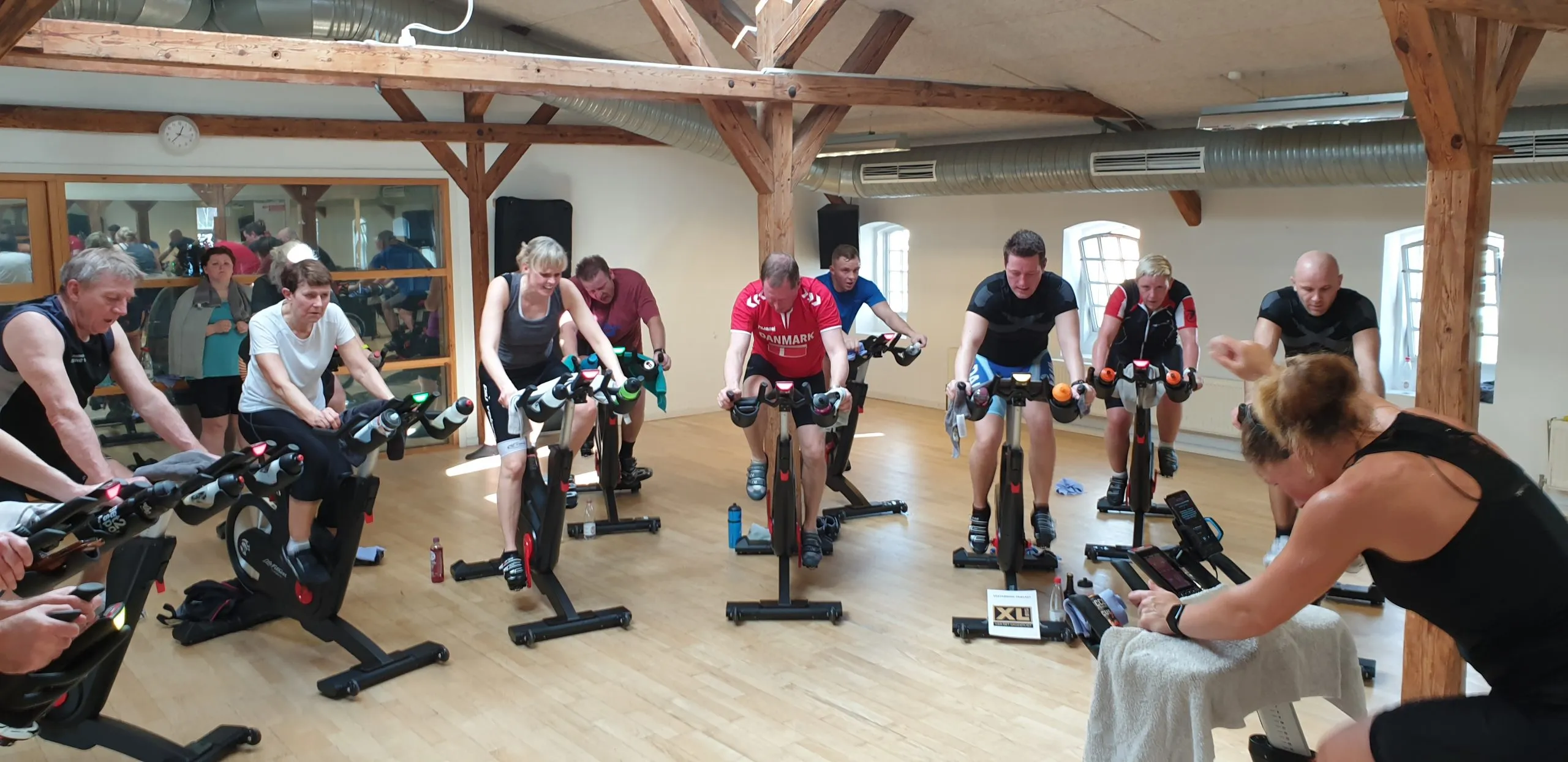 Cardio cykling-hold i holdsalen med instruktøren foran deltagerne