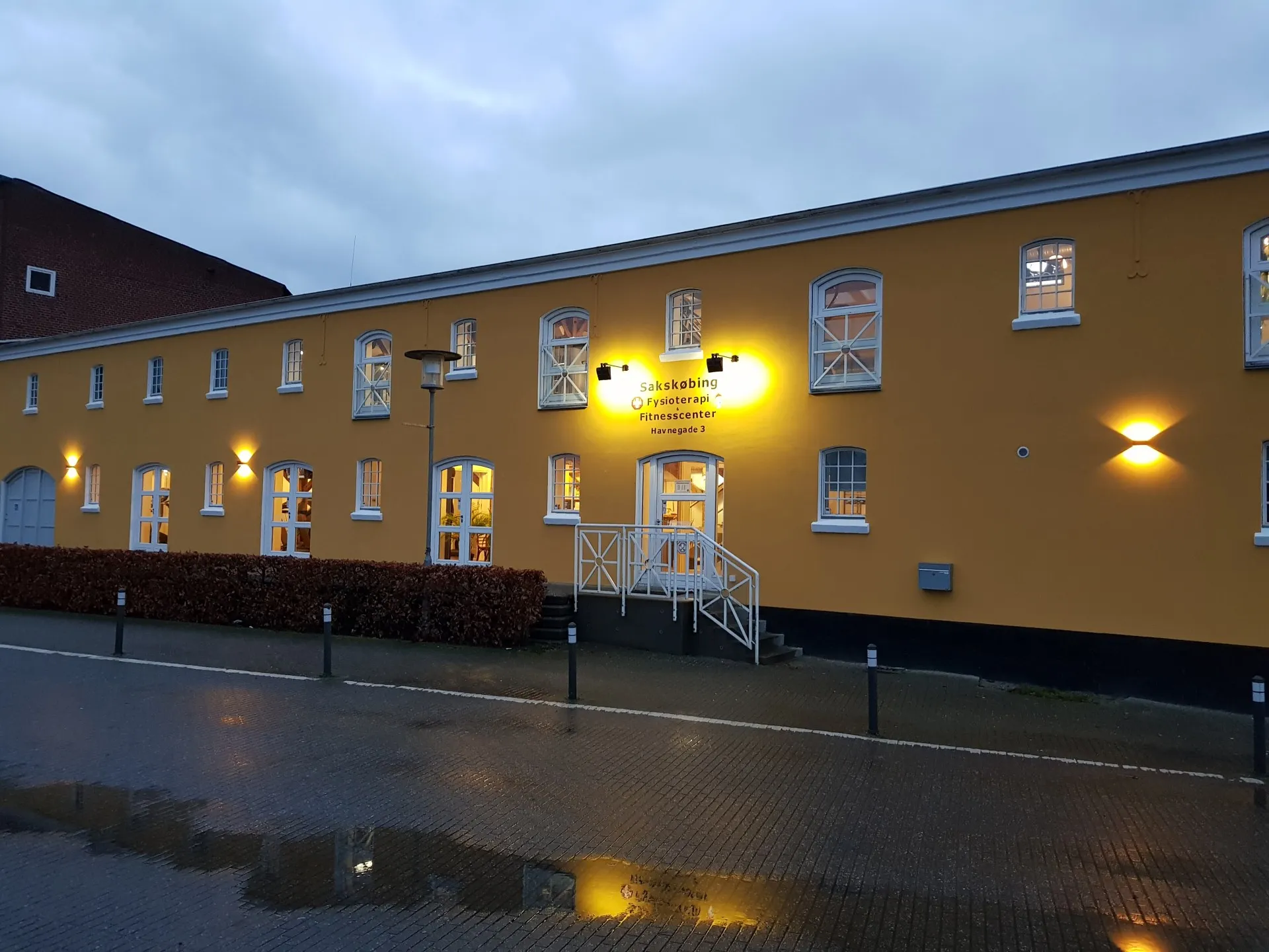 Den gule bygning på Havnegade 3 med oplyst indgang i tusmørke