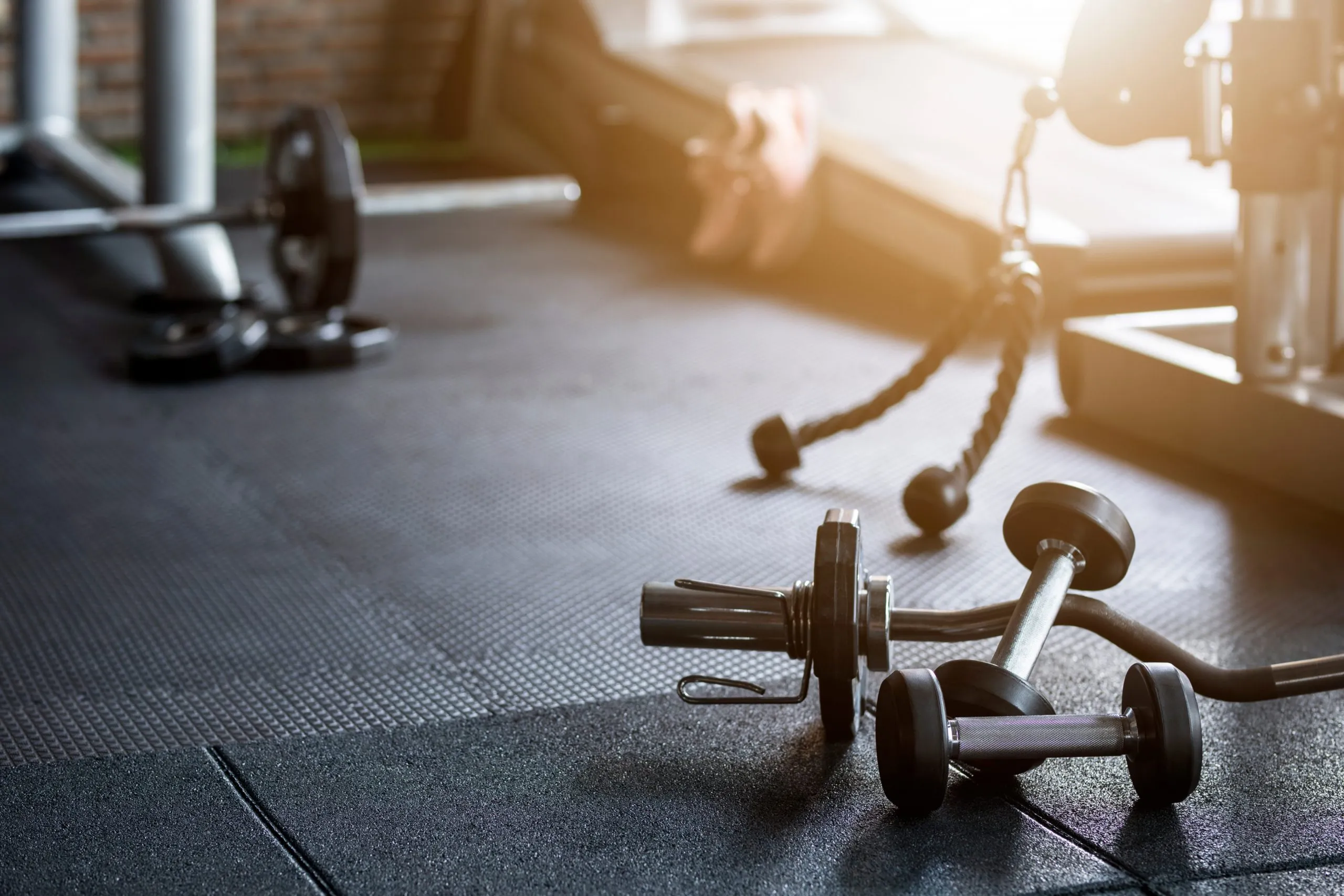 Håndvægte og et kabeltårn i modlys på gulvet i Sakskøbing Fitness Forening