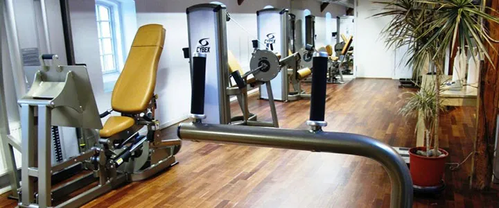 Styrketræningsmaskiner på trægulv på førstesalen i fitnesscenteret