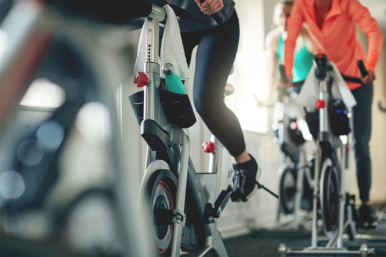 Medlemmer træder på spinningcykler under et cardio cykling-hold